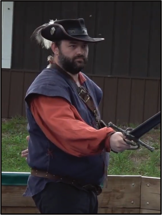 A bearded fighter in a plumed wide-brimmed hat, sword drawn